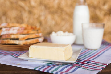 Butter, dairy products and bread on the table against the background of hay