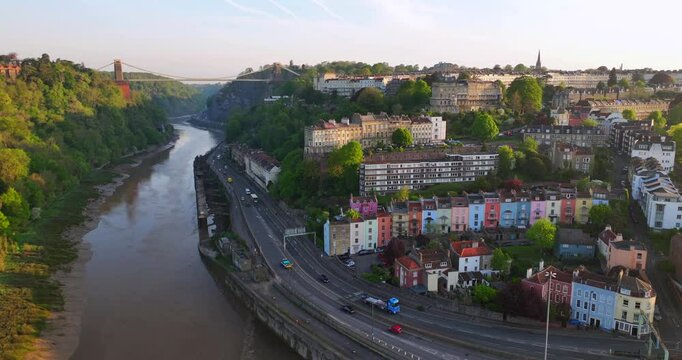 Aerial video of Bristol hillside with multi coloured houses and Clifton Bridge on the background. 