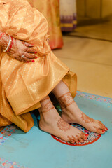 Bride with henna on hands and feet, showcasing a radiant glow in her wedding attire. Intricate...