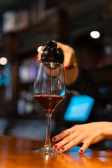 Bartender pouring red wine into glass in restaurant bar