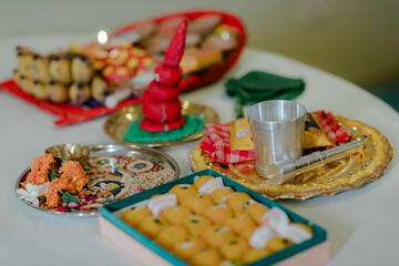 A collection of ritual objects, sweets, and fruits are arranged on decorative plates for a festive celebration, possibly a religious ceremony.