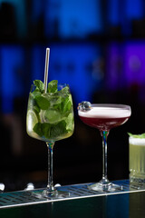 row of various colourfull alcoholic cocktails on a bar desk. Glasses of differen shapes. selective focus