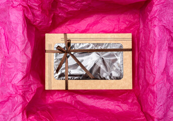 Top view of paper box with bow on the crumpled pink tissue paper. Wrapping gifts, boxes