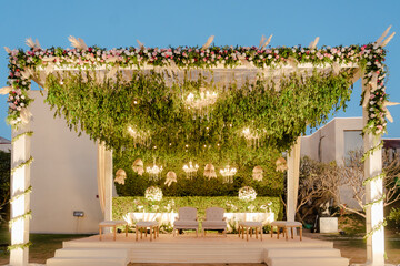 Elegant event stage setup with lush greenery, floral accents, and subtle lighting, perfect for a memorable celebration.
