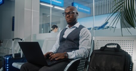 International Airport Terminal: African American Businessman Using Laptop, Drinking Coffee, Sending...