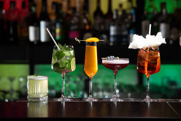 row of various colourfull alcoholic cocktails on a bar desk. Glasses of differen shapes. selective...