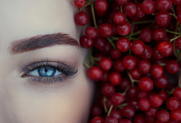 Close-up of a woman's blue eye in red berries.