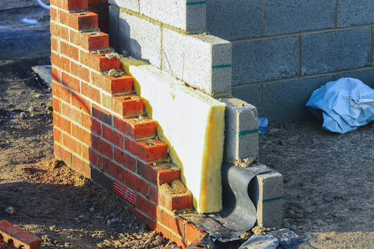Insulating walls of new build houses by placing rock wool inside wall cavities as part of the energy-saving measures. House insulated with mineral wool to reduce energy bill