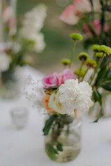 Floral arrangement in a glass jar with white, pink, and green flowers. Soft, romantic, and delicate, perfect for an event or home decor.