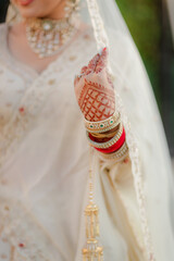 Close up of a bride's adorned hand featuring traditional henna designs, bangles and elegant jewelry...