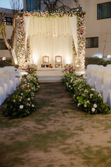 Outdoor event venue setup with floral arrangements creating an inviting ambiance. Chairs are placed under the decorative structure
