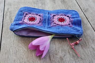 A vibrant crochet piece showcases meticulous hook work. Floral motifs, arranged in squares, dominate the design. A unique and practical zippered crochet pouch for holding small items.