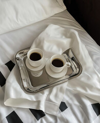 Two coffee cups on vintage silver tray on white bed with checkered blanket — cozy morning scene
