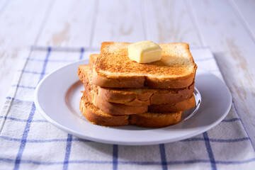 Slices of toast bread and butter on a wooden table, selective focus.