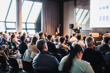 Obraz premium Speaker giving a talk in conference hall at business event. Rear view of unrecognizable people in audience at the conference hall. Business and entrepreneurship concept