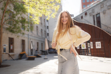 Fototapeta premium Young woman enjoys sunny day outdoors in urban courtyard while posing for camera
