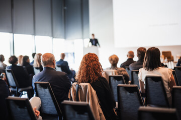 Speaker giving a talk in conference hall at business event. Rear view of unrecognizable people in...