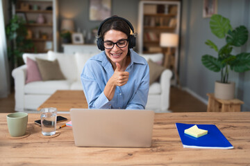 Young freelance business woman having video call conference on laptop computer while sitting and...