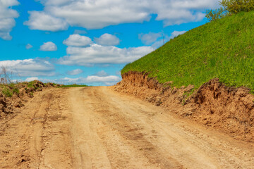 Dirt country road laid on a slope, cut section of soil on a slope