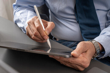 Senior businessman signing digital document on tablet with stylus