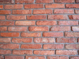 Close-up of a red brick wall with visible mortar, showing texture, pattern, and color variations of...