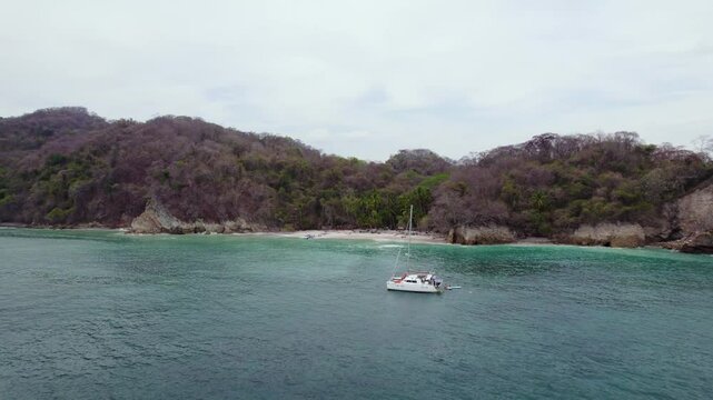 Aerial view of pontoon sailboat floating in Curu Bay with forest and cloudy sky