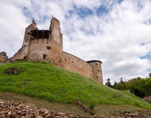 Zborov Castle ruins in Slovakia with scaffolding during restoration. Medieval stone fortress on grassy hill under a cloudy sky.