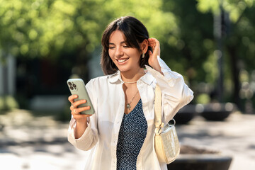 Weekend away. Smiling woman with short trendy hairstyle checking an app on her phone in the city. Browsing online shops, chatting with friends and family or checking the map for directions