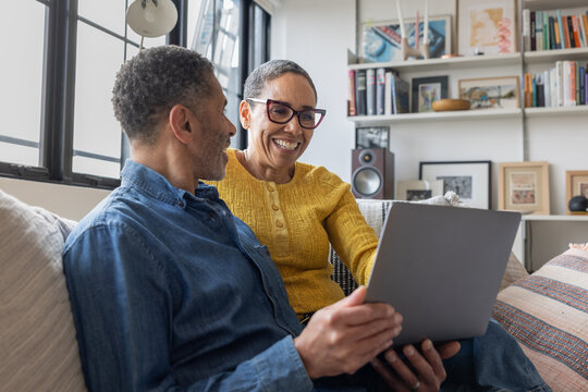 Happy mature woman looking at finances on their laptop with her partner