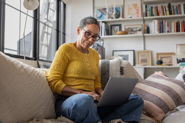 Thoughtful mature Woman Concentrating On Laptop At Home