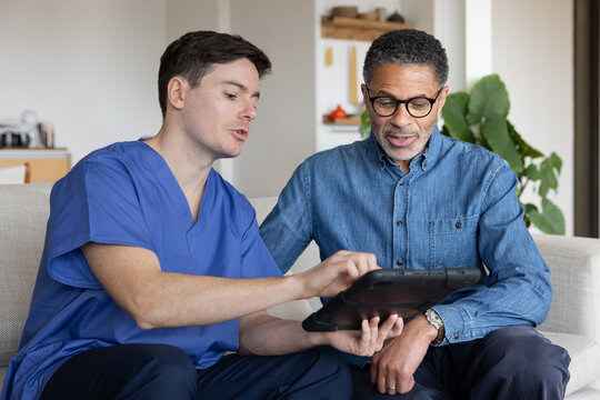 Private healthcare nurse using a digital tablet for a patient health check in their home