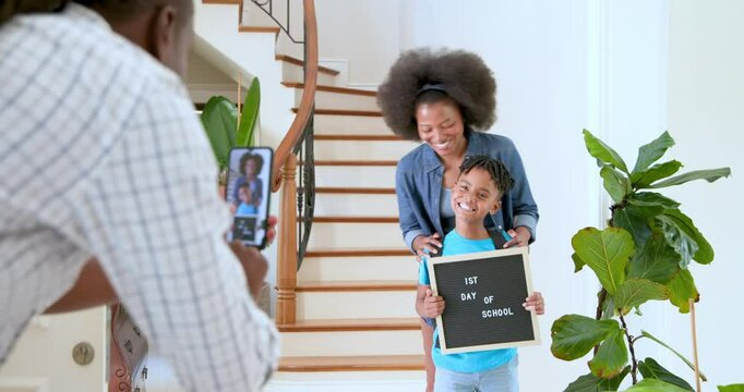 Happy black couple and their multiracial son taking photo of their son on his first day at school, b - Powered by Adobe