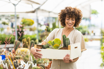 Woman holding a crate of succulents and cacti in a greenhouse
