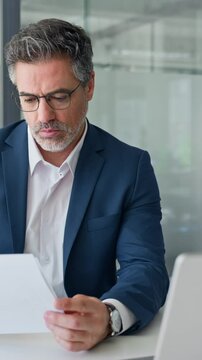 Busy financial specialist senior man working with finance sales document report and pc laptop computer in office. Executive businessman professional doing analysing paperwork business review. Vertical