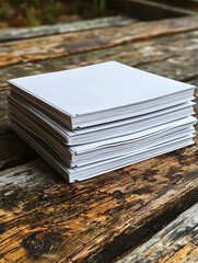 A stack of blank square paper sits on weathered wooden planks creating a simple rustic composition.