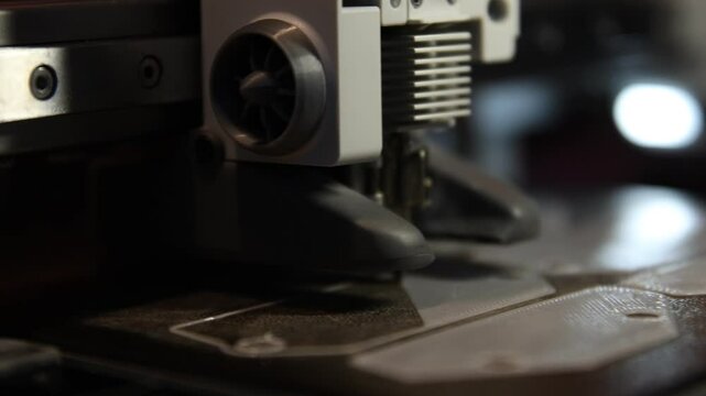 Close-up of a 3D printer in action, creating a plastic object layer by layer. 