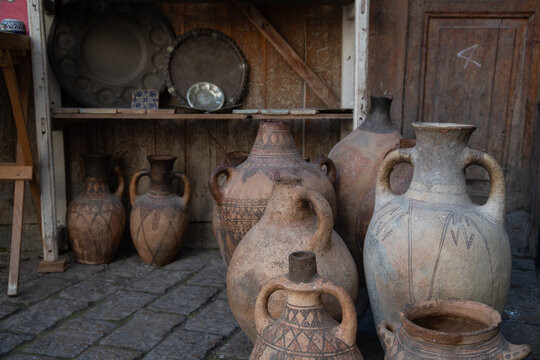 Ancient clay jugs and pots displayed in rustic setting of Fez