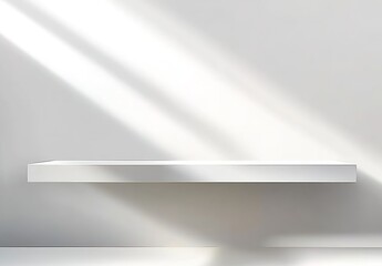 A white shelf mounted on a white wall with light and shadows cast on the wall.