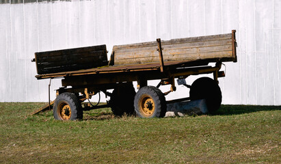 An old, broken trailer on a farm on wheels.