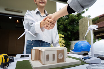 Sustainability engineers shaking hands over architectural design