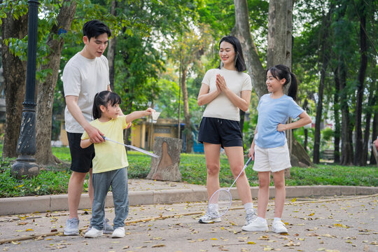 Family enjoying outdoor activities and bonding in a park during a sunny day while playing badminton and having fun together