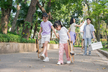 Obraz premium Children enjoy outdoor playtime while carrying folding chairs in a sunny park during afternoon hours