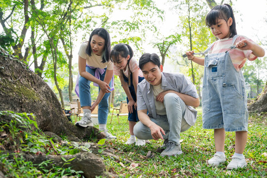 Family enjoying outdoor activities together in a park surrounded by trees and greenery on a sunny day
