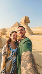 Tourists taking selfie with great sphinx of giza and pyramid of khafre in background