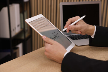 Electronic signature. Man using stylus and tablet at wooden table indoors, closeup