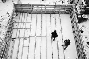 Construction workers laying foundation in snowy environment