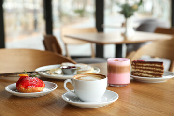Aromatic coffee and delicious desserts served on wooden table in cafe