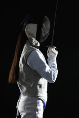 Fencer with epee on black background. Combat sport
