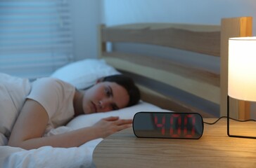 Frustrated young woman suffering from insomnia on bed indoors, selective focus
