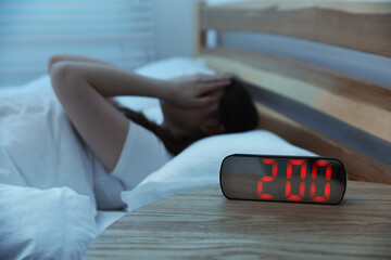 Frustrated young woman suffering from insomnia on bed indoors, selective focus